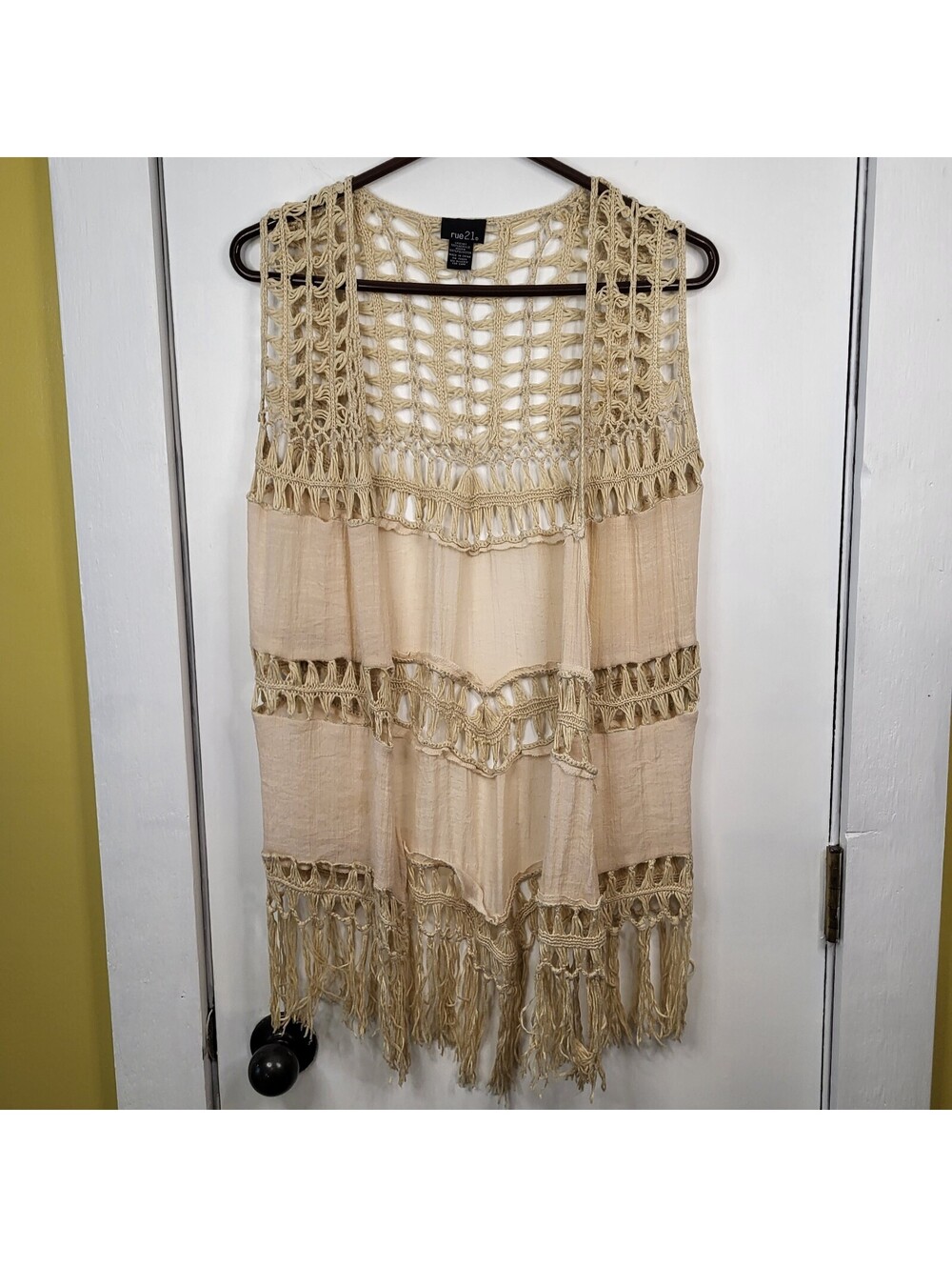 rue21 vest features a beige, open-knit crochet design with long fringe details.